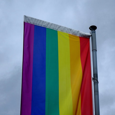 Regenbogenflagge vor dunklen Wolken