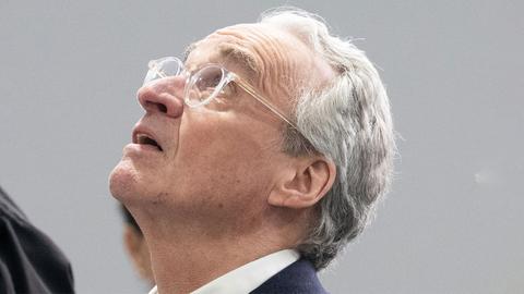 Ein Mann mit grauem Haar und transparenter Brille legt den Kopf in den Nacken und schaut nach oben.