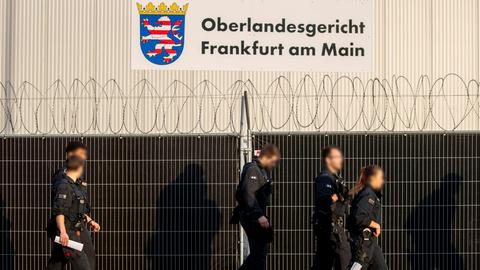 Polizisten gehen unter dem Schriftzug "Oberlandgericht Frankuft am Main" auf dem Gelände der Notbehilfshalle in der Außenstelle Sossenheim des Oberlandesgericht Frankfurt. 