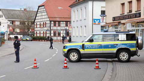 Polizeiauto und Polizeikräfte auf einer Straße, welche den Straßenabschnitt absperren.