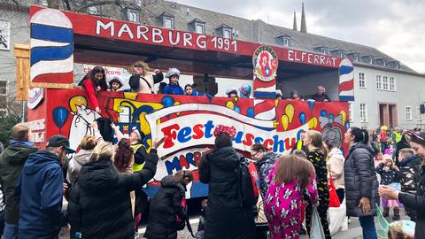 Motivwagen des Elferrats beim Rosenmontagsumzug in Marburg, kostümierte Zuschauer stehen davor