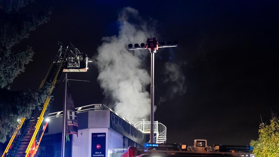 Rauch steigt aus einem Haus auf, Drehleiter der Feuerwehr im Vordergrund