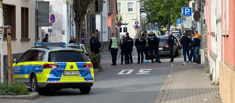 Polizei und Zeugen stehen auf einer abgesperrten Straße am Tatort in Rüsselsheim.