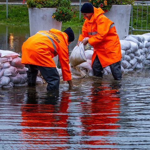 Feuerwehrleute bauen mit Sandsäcken einen Schutzwall Hochwasser.