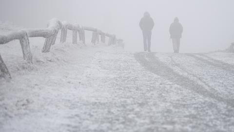 Spaziergänger gehen auf dem Großen Feldberg durch den Schnee.