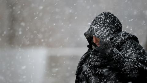 Eine Passantin zieht sich bei Schneefall die Kapuze über den Kopf