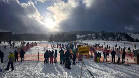 Mehrere Menschen vor einer kalten Wintersonne in Skikleidung