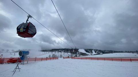 Eine Gondel der Ettelsbergseilbahn vor dem verschneiten Berg und Himmel