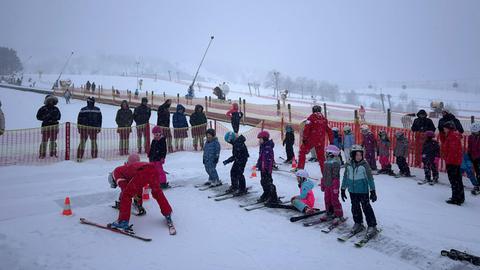 Kinder stehen bei einem Skikurs in einer Reihe