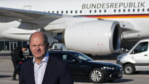 Scholz steht mit verkniffenem Gesichtsausruck vor einem Flugzeug mit Aufdruck Bundesrepublik