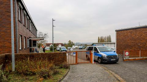 Das Bild zeigt die Polizeistation in Schwalmstadt. Zu sehen ist ein Gebäude aus rotem Backstein mit einem rostroten Zaun davor. Die Zufahrt ist durch ein Polizeiauto blockiert. Im Hintergrund sind Ermittler der Spurensicherung zu sehen.