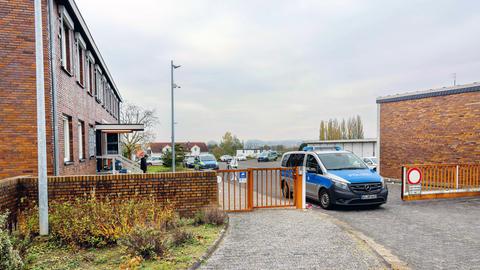 Das Bild zeigt die Polizeistation in Schwalmstadt. Zu sehen ist ein Gebäude aus rotem Backstein mit einem rostroten Zaun davor. Die Zufahrt ist durch ein Polizeiauto blockiert. Im Hintergrund sind Ermittler der Spurensicherung zu sehen.