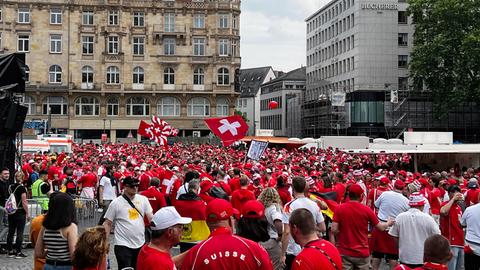 Viele Schweizer Fußballfans stehen versammelt auf dem Roßmarkt und schwenken Fahnen.
