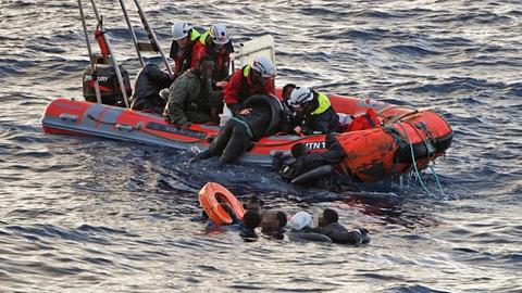 Seenotretter von der "Sea Punk One" ziehen im Wasser schwimmende Menschen in das Beiboot. 