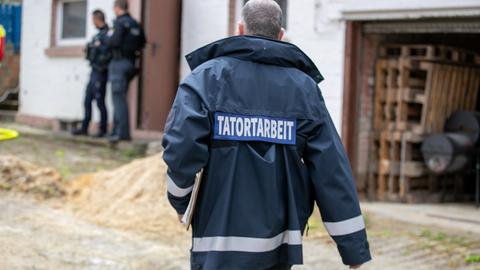 Das Bild zeigt einen Polizisten von hinten. Er trägt kurze graue Haare und eine blaue Jacke, auf der das Wort "Tatortarbeit" steht.