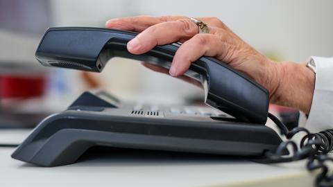 Eine Frau nimmt einen Telefonhörer in die Hand.