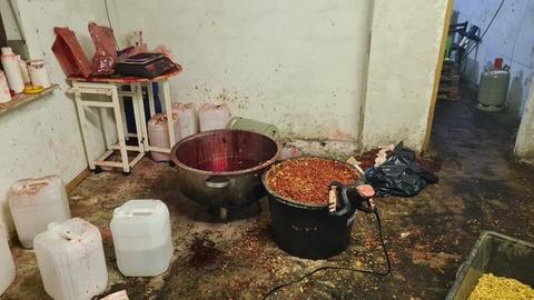 Ein verdreckter Raum mit mehreren weißen Kanistern, Gaskartuschen und schwarzen Wannen mit Tabak