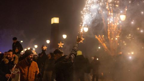 Menschen feiern den Jahreswechsel an Silvester in Frankfurt.