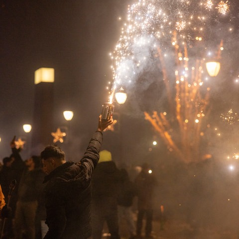 Menschen feiern den Jahreswechsel an Silvester in Frankfurt.