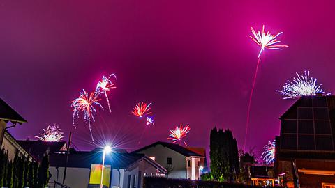 Raketen erleuchten den Nachthimmel, der in pink erscheint.