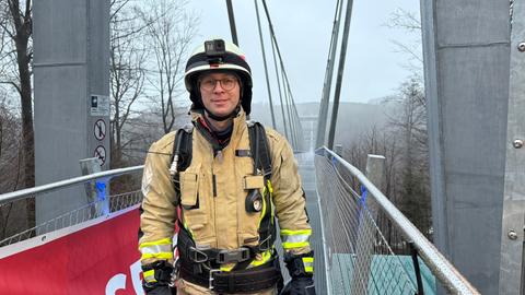 Ein Feuerwehrmann steht in voller Montur auf dem Skywalk in Willingen