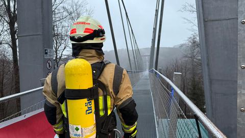 Ein Feuerwehrmann steht in voller Montur auf dem Skywalk in Willingen