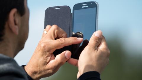 Ein Mann hält ein Smartphone mit Klapphülle in der Hand.