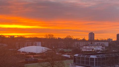 Rot-orange gefärbter Himmel über Sportplatz und Häusern.