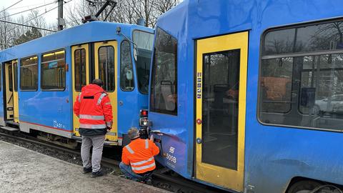 Zwei Straßenbahnen stehen kaputt auf den Gleisen, Einsatzkräfte begutachten den Schaden.