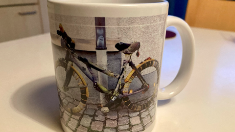 Tasse mit Fahrrad-Motiv. Das Fahrrad ist umstrickt mit Wolle.