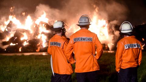 Feuerwehrleute beim nächtlichen Strohballen-Löschen