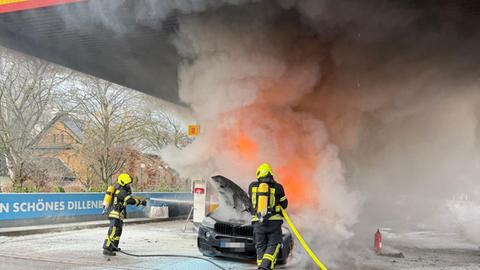 Feuerwehrkräfte löschen brennendes Auto auf Tankstellengelände