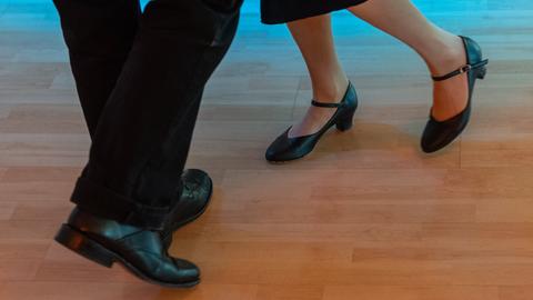 Frau tanzt mit Mann auf Parkett, nur Schuhe zu sehen