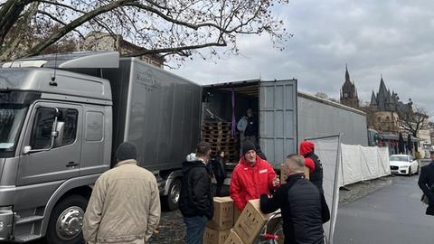 Ein Container steht an einer Straße am Frankfurter Mainufer, Männer laden Paletten mit zurückgegebenen Weihnachtsmarkt-Tassen auf.