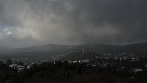 Sonnenlicht fällt durch eine Wolkendecke auf die Stadt Königstein im Taunus mit ihrer Burgruine