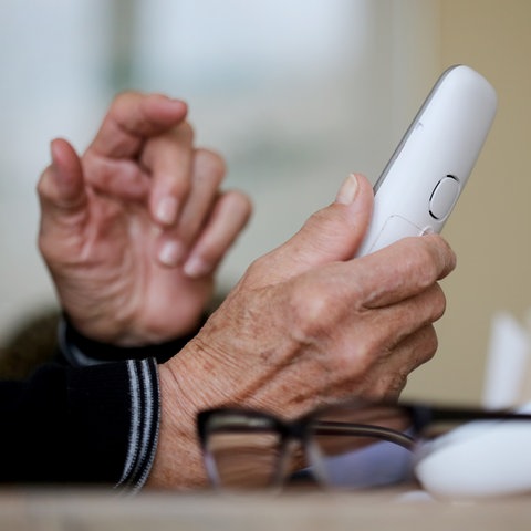 Eine ältere Person geht an ihr schnurloses Festnetztelefon. 