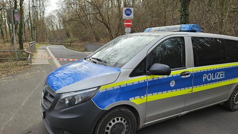 Ein Einsatzfahrzeug der Polizei steht auf einer Straße vor Bäumen.