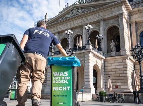 Ein Mitarbeiter der Stadtreinigung stellt vor der Alten Oper Mülltonnen auf.