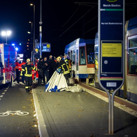 Einsatzkräfte von Polizei und Feuerwehr stehen im Dunkeln neben einer Straßenbahn.