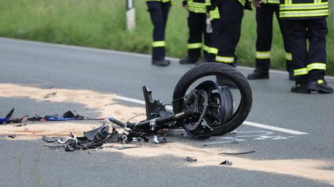 Das Motorrad wurde in zwei Teile gerissen. Einer liegt auf der Fahrbahn, Feuerwehrleute stehen drum herum.