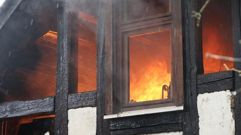 Flammen im Inneren eines Fachwerkhauses, durch die Fenster aufgenommen