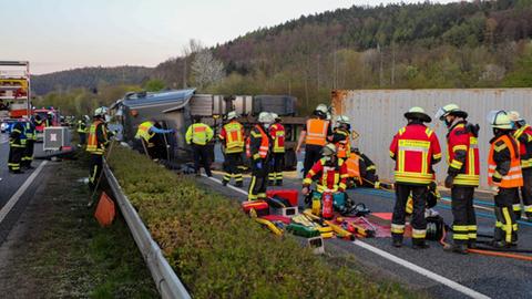 Feuerwehrleute vor quer auf einer Autobahn liegendem Lastwagen.