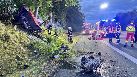 Stark zerstörtes Auto neben der Fahrbahn, Einsatzkräfte daneben