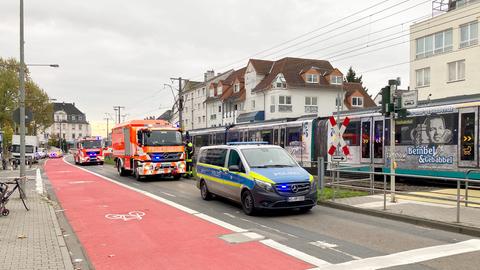 Polizeiautos und orangfarbene Rettungswagen stehen auf der Straße neben einer Straßenbahn und einem Fußgängerübergang.