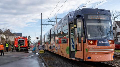 Feuerwehr-Mitarbeiter stehen neben einer Straßenbahn auf einer Straße