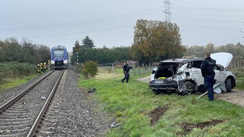 Gleise mit Zug, daneben Unfall-Auto