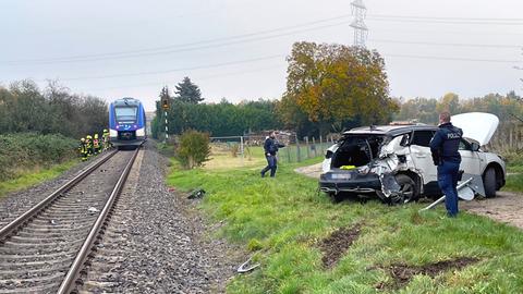 Gleise mit Zug, daneben Unfall-Auto