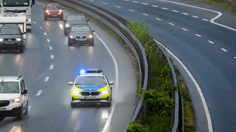 Polizeiauto mit Blaulicht auf Autobahn neben anderen Fahrzeugen