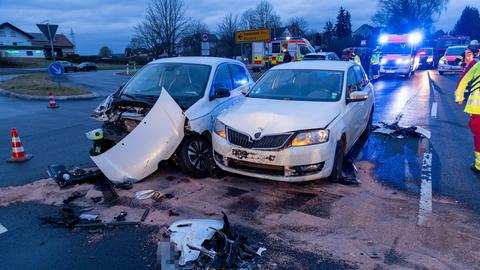 Zwei weiße Kleinwagen stehen nebeneinander auf der Fahrbahn, eines ist sehr stark beschädigt. 