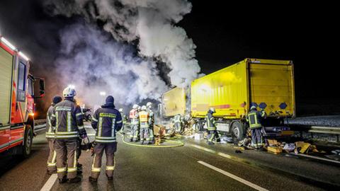 Feuerwehrleute löschen brennenden Paketlaster, Laster qualmt, Ladung (Pakete) liegen teilweise herum